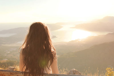 Rear view of woman standing on mountain against sky