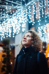 Curly young woman in night festive lights