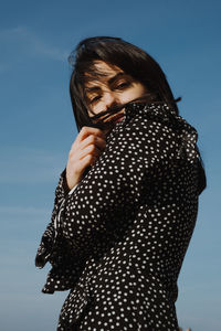 Portrait of a beautiful young woman against sky