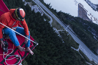 Man sitting on portaledge putting his climbing shoes on at sunset