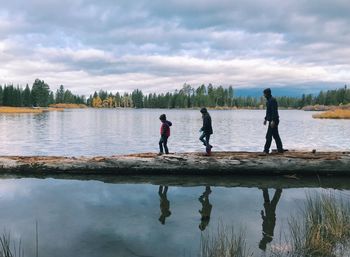 People on lake against sky