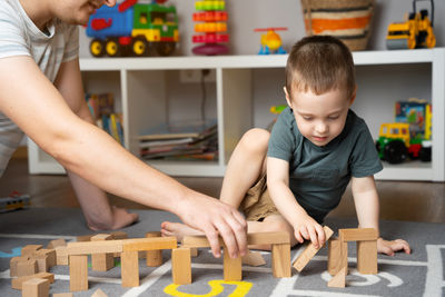 Little toddler boy playing wooden blocks with dad. spending time 