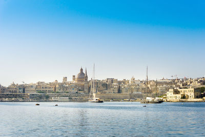 Buildings by sea against blue sky