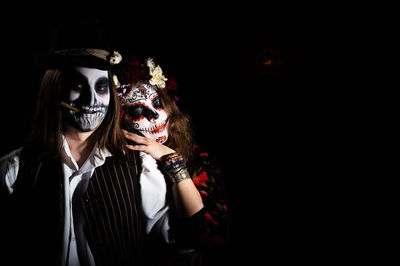 Portrait of woman wearing mask against black background