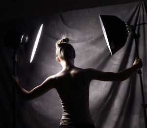 Rear view of woman holding lighting equipment in studio