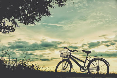 Silhouette bicycle on field against sky