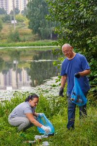 A man and a woman clean up a garbage dump in the nature. vertical photo