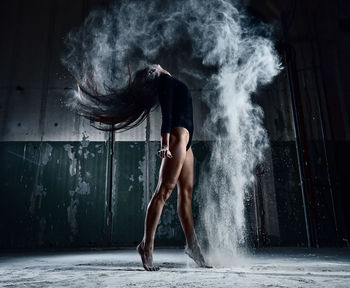 Full length of woman powder dancing in abandoned house