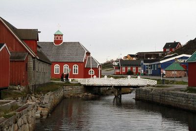 Houses by river against sky