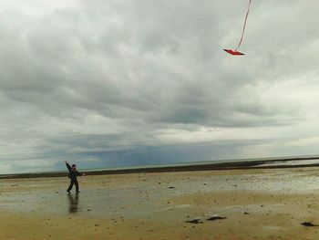 Man surfing on beach against sky