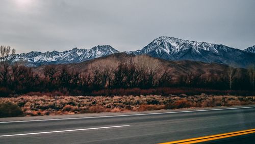 Road by snowcapped mountains against sky