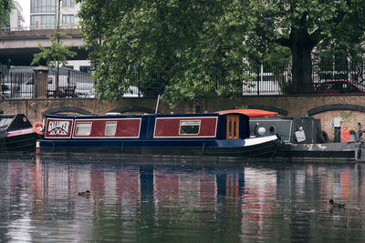 Boat moored in canal by trees in city