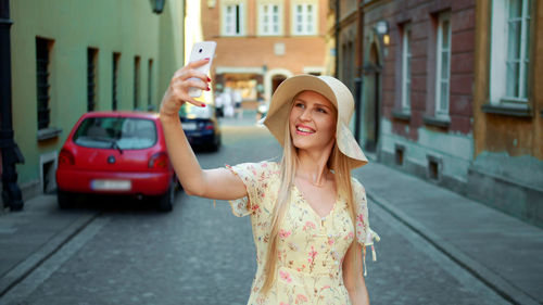 Portrait of young woman standing against building