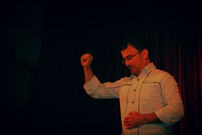 Midsection of man standing by illuminated stage