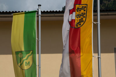 Multi colored flags against yellow wall in city