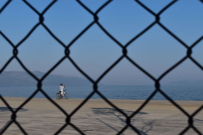 Scenic view of sea seen through chainlink fence