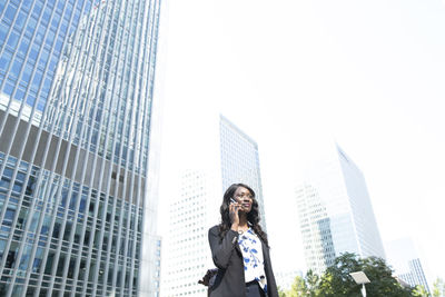 Low angle view of woman standing on building against sky