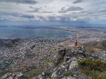 Woman standing on mountain against cityscape