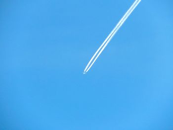 Low angle view of airplane flying against clear blue sky