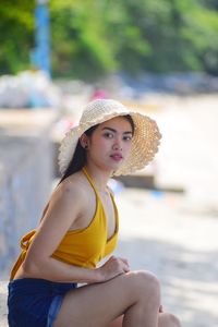 Portrait of young woman sitting against blurred background