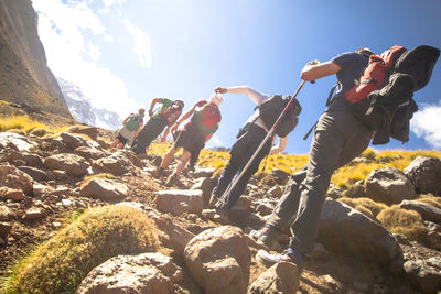 Low angle view of people hiking on mountains against sky