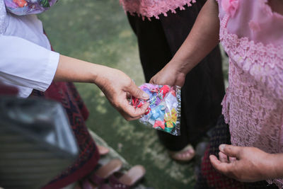 Cropped image of woman giving plastic bag to friend