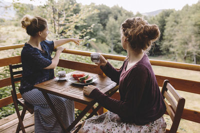 Two women sitting on balcony and drinking coffee