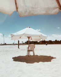 Traditional umbrella and chair on beach against sky