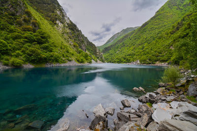 Scenic view of lake by mountains against sky