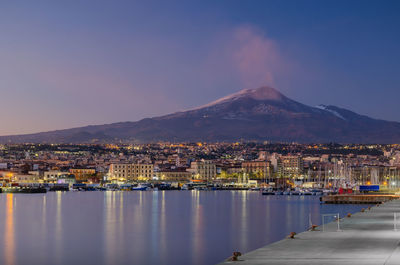 Aerial view of townscape by sea against sky at night