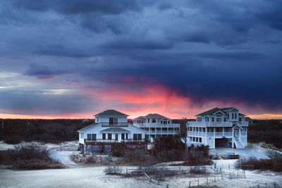 Houses against dramatic sky during sunset