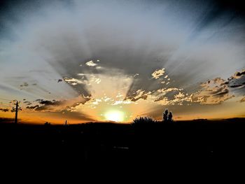 Silhouette trees on field against sky during sunset