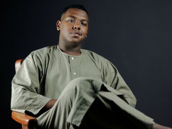 Portrait of young man standing against black background