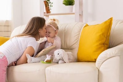 Mother and daughter sitting on sofa at home