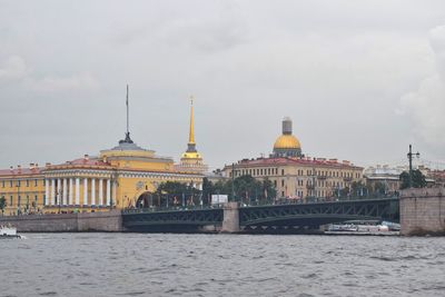 View of buildings by sea against cloudy sky