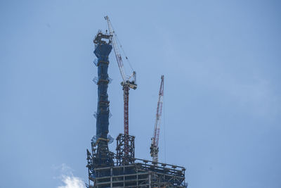 Low angle view of cranes against sky