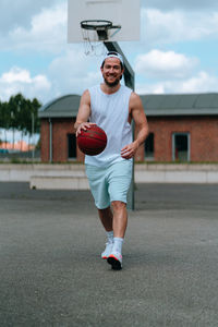 Portrait of mid adult man playing with basketball in court