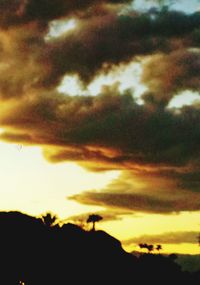 Low angle view of silhouette trees against dramatic sky