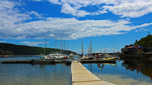 Boats moored at harbor against sky