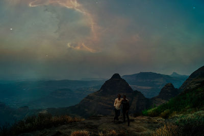 Man standing on mountain against sky during sunset