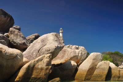 Low angle view of rocks against clear blue sky