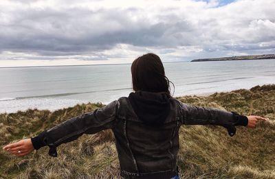 Woman with arms outstretched standing at beach