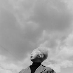 Low angle view of girl looking away against sky