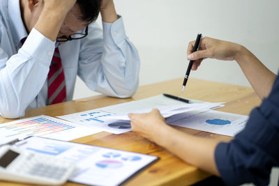 Midsection of man holding umbrella on table