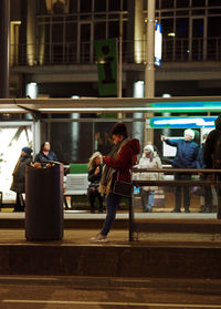 People sitting on railroad tracks in city at night