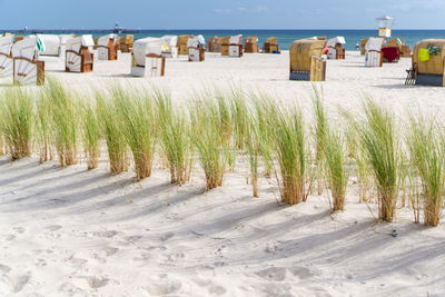 Hooded chairs on beach against sky