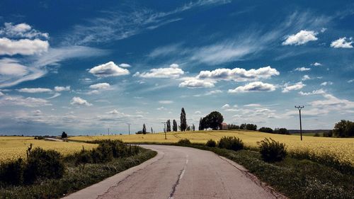 Road amidst field against sky