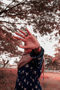 Midsection of woman standing by tree against plants