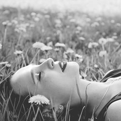 Close-up of young woman with flowers in field