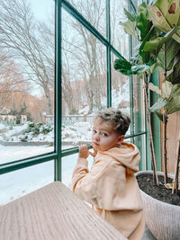 Portrait of cute baby boy sitting on window